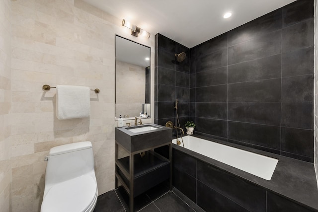 bathroom featuring tile patterned floors, tiled shower / bath, toilet, vanity, and tile walls