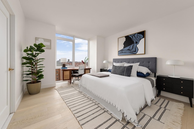 bedroom featuring expansive windows and light wood finished floors