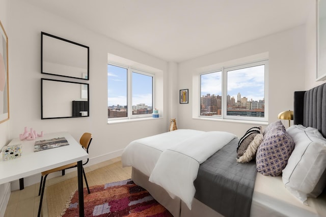 bedroom with baseboards, a city view, and wood finished floors
