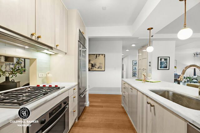212 E 95th St Unit 2Ab, New York City, NY 10128 - kitchen featuring a sink, appliances with stainless steel finishes, light wood-style flooring, tasteful backsplash, and hanging light fixtures
