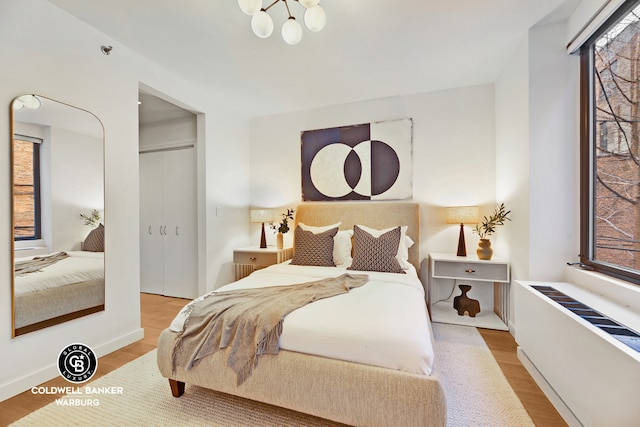 212 E 95th St Unit 2Ab, New York City, NY 10128 - bedroom featuring radiator, a closet, wood finished floors, and a chandelier