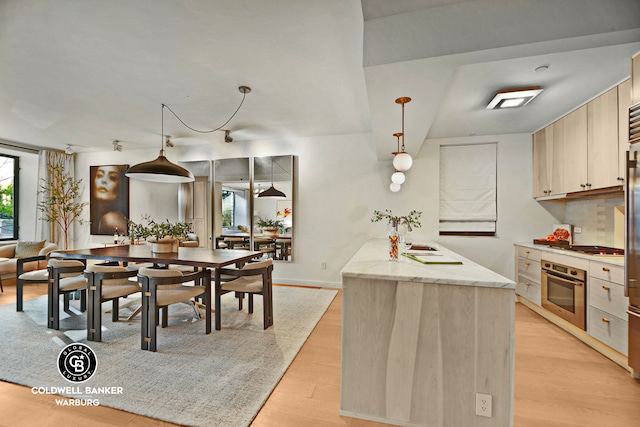 212 E 95th St Unit 2Ab, New York City, NY 10128 - kitchen with stainless steel oven, light wood-style floors, light stone counters, backsplash, and hanging light fixtures