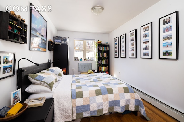 bedroom with wood finished floors and a baseboard radiator