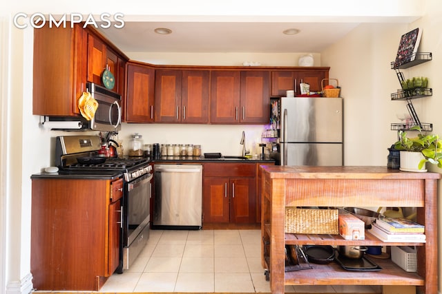 kitchen featuring light tile patterned floors, stainless steel appliances, a sink, and dark countertops