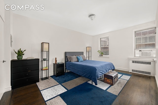 bedroom featuring baseboards, wood finished floors, radiator heating unit, and cooling unit