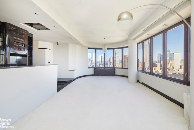 330 E 38th St Unit 51Ef, New York City, NY 10016 - carpeted spare room featuring a view of skyline and baseboards