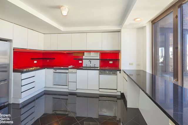 330 E 38th St Unit 51Ef, New York City, NY 10016 - kitchen featuring white dishwasher, wall oven, dark tile patterned floors, white cabinets, and dark countertops