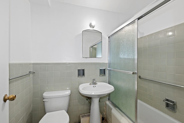 235 Adams St Unit 6A, New York City, NY 11201 - full bathroom with tile walls, a wainscoted wall, toilet, a sink, and bath / shower combo with glass door