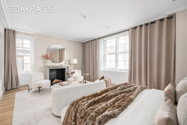 bedroom with light wood finished floors, a fireplace, and ornamental molding