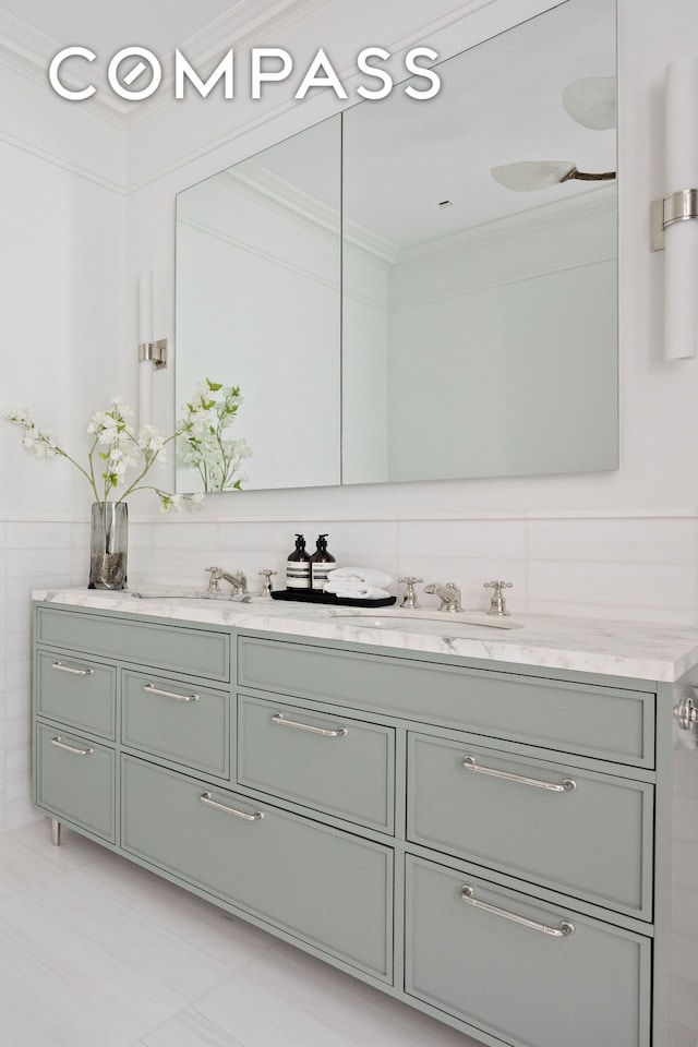 bathroom featuring crown molding, double vanity, tile patterned floors, and tile walls