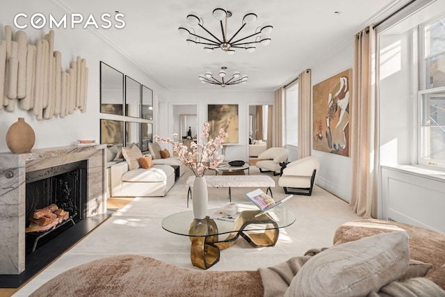 living area featuring healthy amount of natural light, a chandelier, ornamental molding, and a premium fireplace