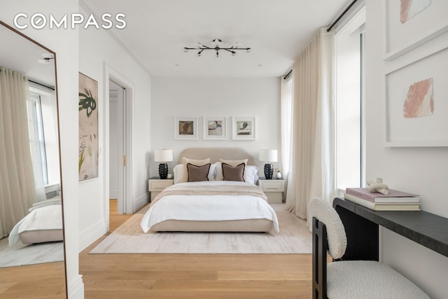bedroom with light wood-style floors, multiple windows, and baseboards