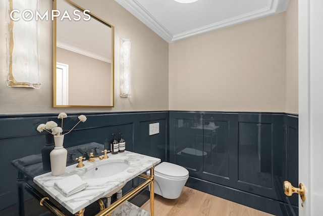 bathroom featuring crown molding, toilet, a wainscoted wall, wood finished floors, and vanity