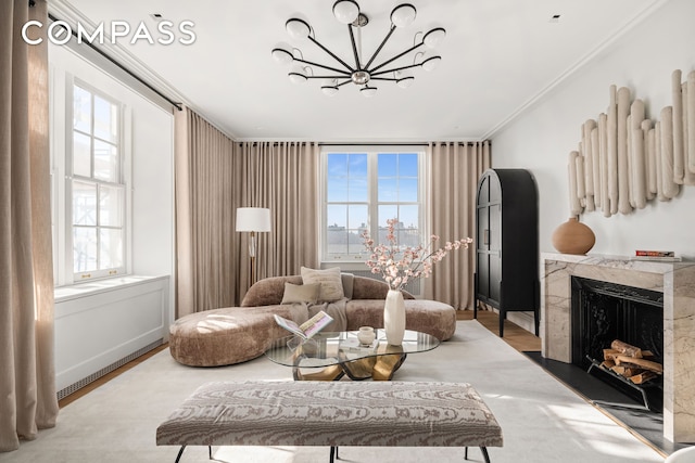 living room featuring crown molding, a chandelier, wood finished floors, and a premium fireplace