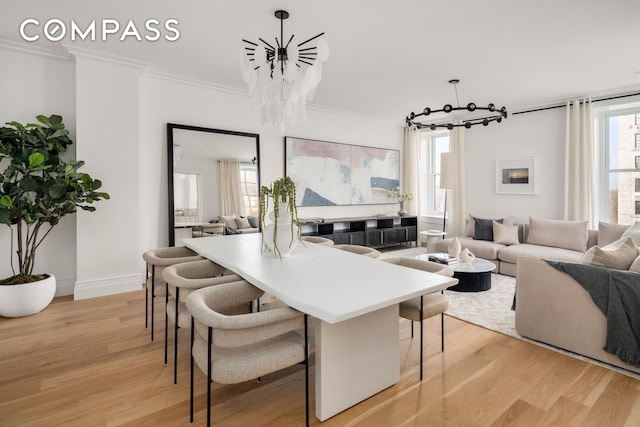 dining space with a chandelier, light wood finished floors, crown molding, and baseboards