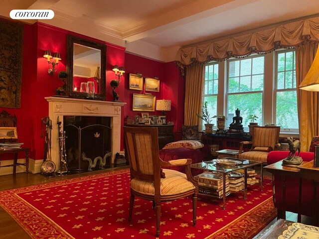 sitting room with a fireplace with flush hearth, baseboards, wood finished floors, and crown molding