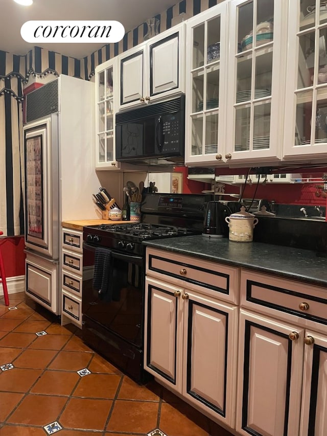 444 E 57th St Unit 5C, New York City, NY 10022 - kitchen with black appliances, wallpapered walls, dark tile patterned flooring, dark countertops, and glass insert cabinets