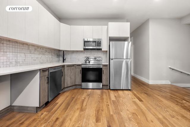 680-682 Hendrix St, New York City, NY 11207 - kitchen with stainless steel appliances, baseboards, a sink, light wood-style floors, and decorative backsplash