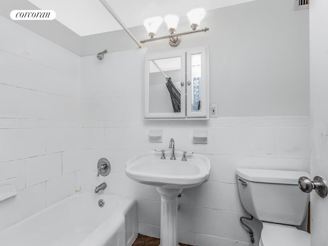 bathroom featuring visible vents, toilet, tile walls, tub / shower combination, and wainscoting