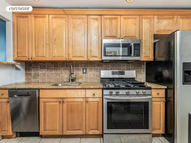 kitchen with tasteful backsplash, light stone countertops, a sink, and appliances with stainless steel finishes