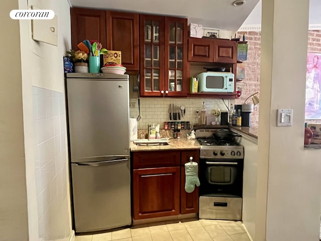 304 E 73rd St Unit 5E, New York City, NY 10021 - kitchen featuring stainless steel appliances, light tile patterned flooring, reddish brown cabinets, tasteful backsplash, and glass insert cabinets