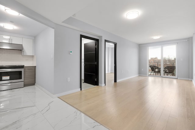 70-09 45th Ave Unit 6D, New York City, NY 11377 - kitchen featuring stainless steel electric stove, under cabinet range hood, decorative backsplash, white cabinets, and baseboards