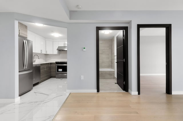 70-09 45th Ave Unit 6D, New York City, NY 11377 - kitchen with appliances with stainless steel finishes, under cabinet range hood, baseboards, and light countertops
