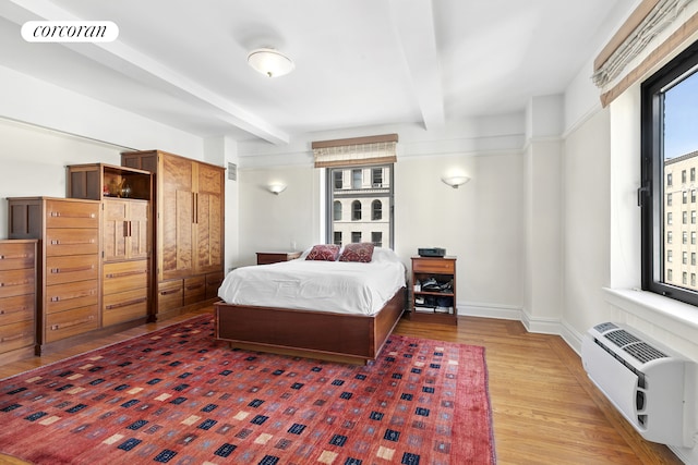bedroom with beamed ceiling, an AC wall unit, wood finished floors, and visible vents