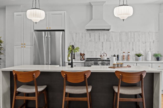 kitchen featuring decorative light fixtures, stove, high end refrigerator, premium range hood, and light countertops