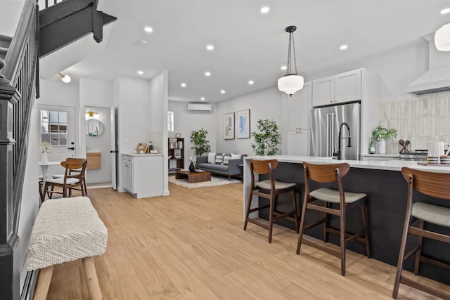 kitchen with light countertops, an AC wall unit, a kitchen breakfast bar, decorative backsplash, and high quality fridge
