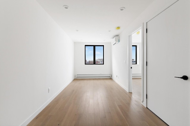 corridor with a baseboard radiator, an AC wall unit, wood finished floors, and baseboards