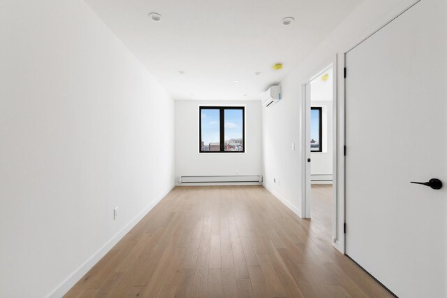 800 5th Ave Unit 2A, New York City, NY 11232 - unfurnished room featuring a baseboard radiator, an AC wall unit, wood finished floors, and baseboards