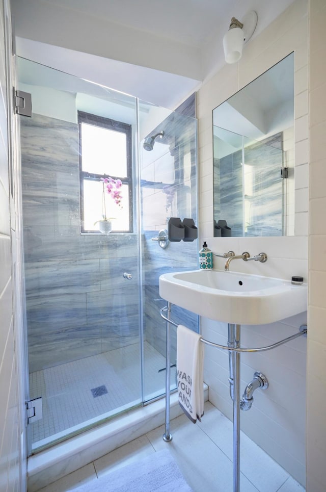 328 W 17th St Unit 5E, New York City, NY 10011 - full bath featuring tile walls, tile patterned floors, a shower stall, and a sink