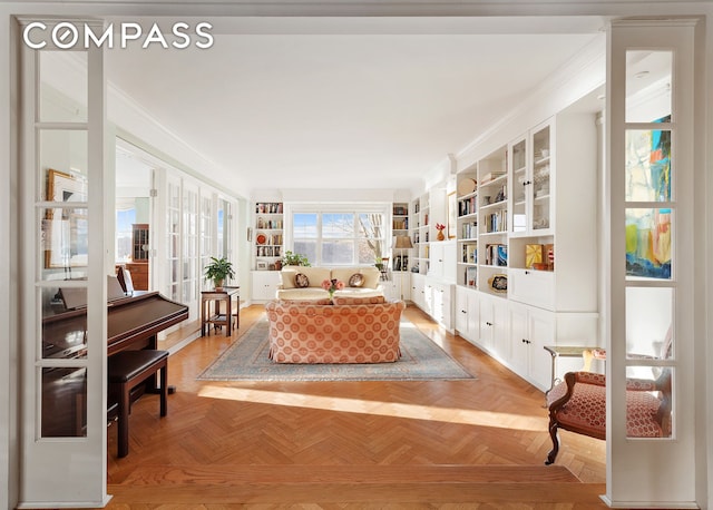 sitting room with ornamental molding, french doors, and built in shelves