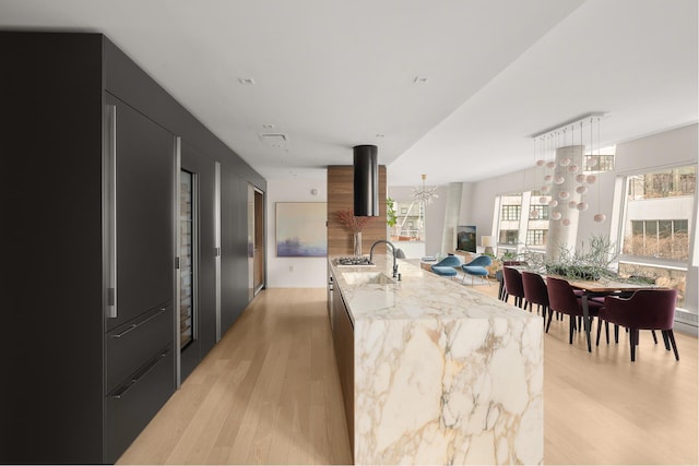 245 10th Ave Unit 3W, New York City, NY 10001 - kitchen featuring dark cabinets, modern cabinets, light wood-style floors, a chandelier, and a sink