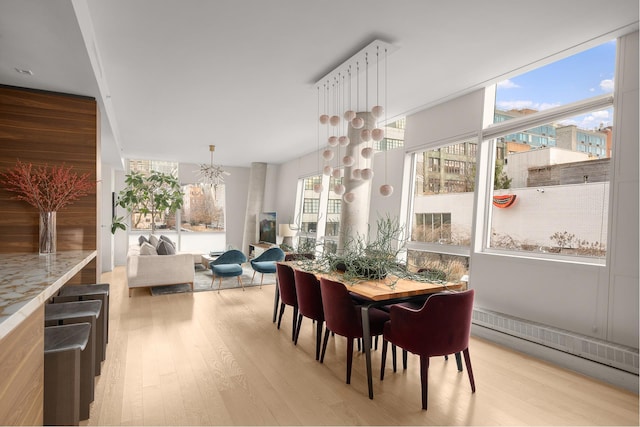 245 10th Ave Unit 3W, New York City, NY 10001 - dining room featuring light wood-type flooring, a chandelier, and a baseboard heating unit