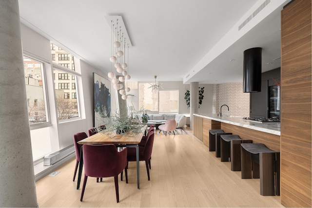 245 10th Ave Unit 3W, New York City, NY 10001 - dining area with healthy amount of natural light, light wood-type flooring, and a chandelier