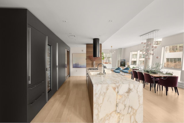 245 10th Ave Unit 3W, New York City, NY 10001 - kitchen featuring dark cabinets, modern cabinets, light wood finished floors, a sink, and pendant lighting