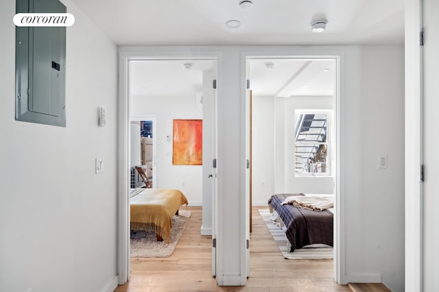 corridor featuring electric panel, light wood-style floors, and baseboards