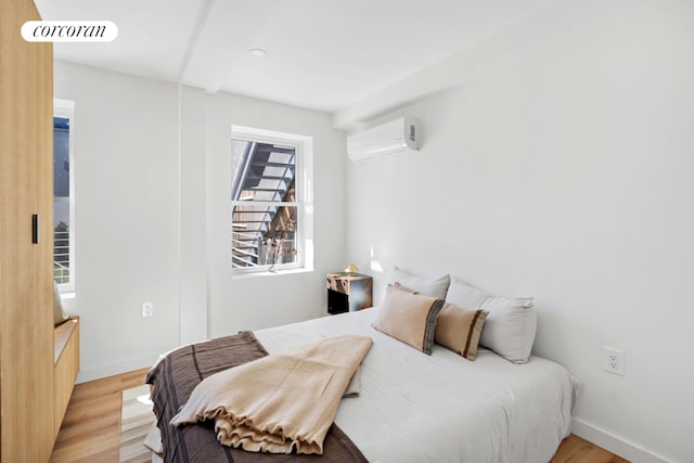 bedroom featuring a wall mounted air conditioner, light wood finished floors, recessed lighting, and baseboards