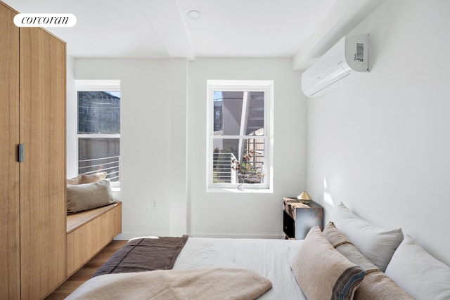 bedroom featuring a wall mounted air conditioner and wood finished floors
