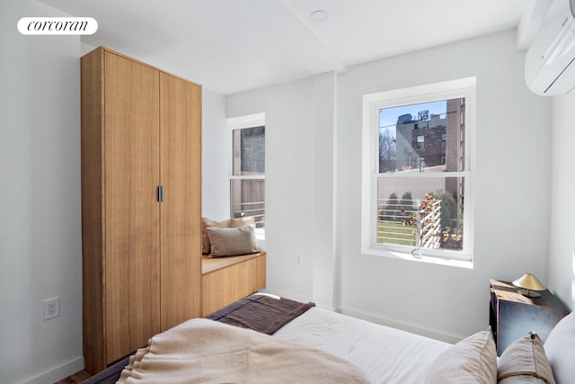 bedroom featuring an AC wall unit and baseboards