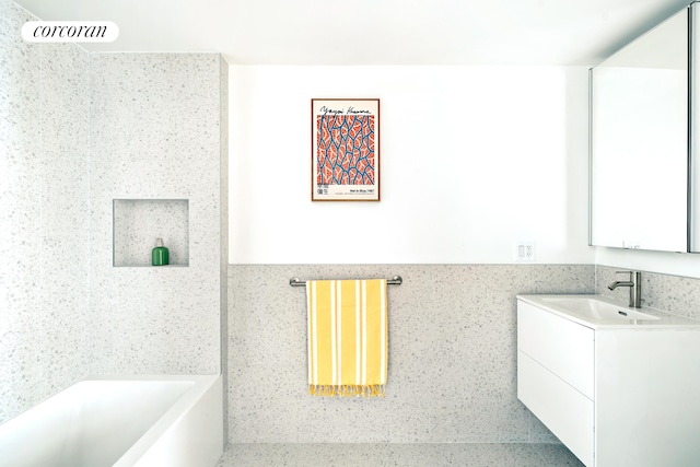 bathroom featuring a tub, vanity, and tile walls