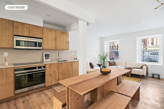 kitchen with stainless steel appliances, a sink, light countertops, light wood-style floors, and modern cabinets