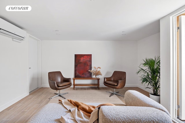 living area with a wall unit AC, light wood finished floors, and baseboards
