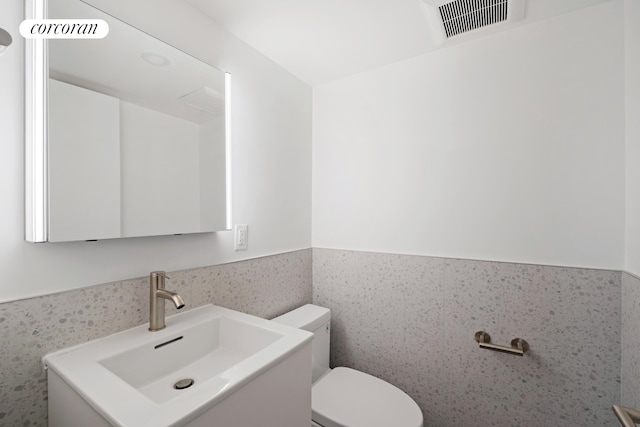 bathroom with toilet, a wainscoted wall, and vanity