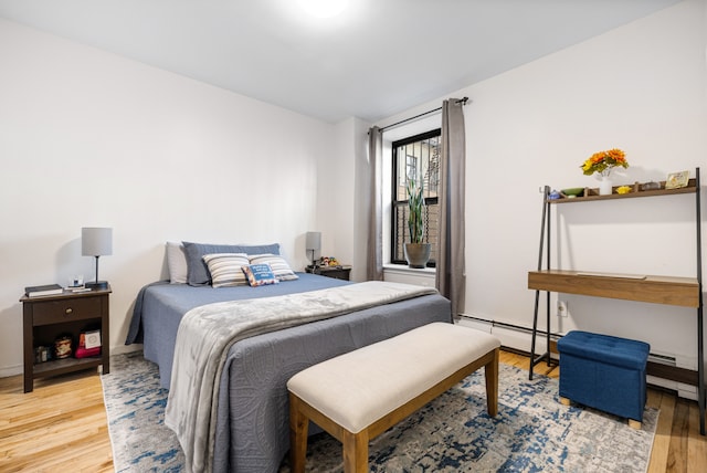 bedroom with a baseboard radiator, baseboard heating, and light wood finished floors