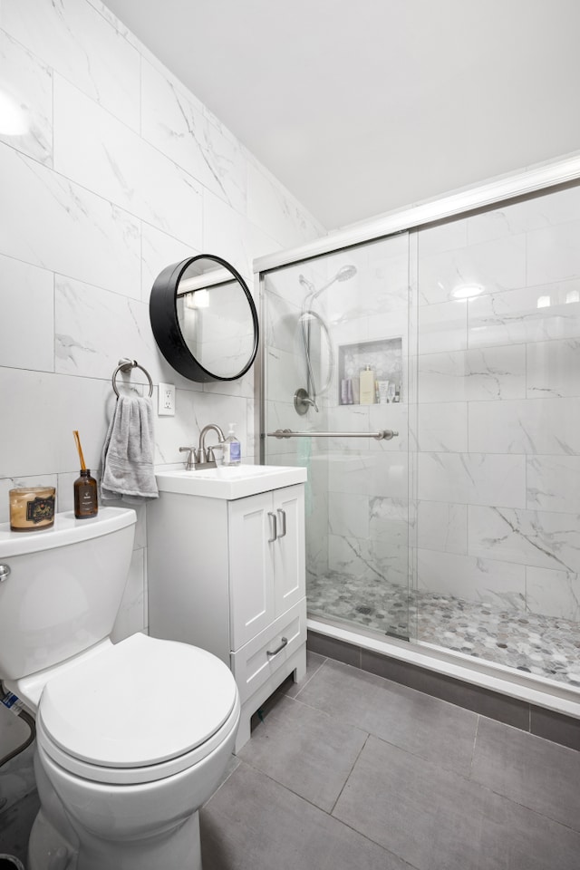 bathroom with vanity, tile walls, a stall shower, and toilet