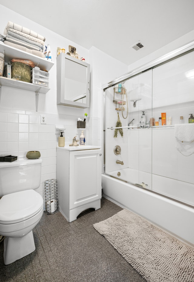 full bath with visible vents, vanity, toilet, a wainscoted wall, and combined bath / shower with glass door