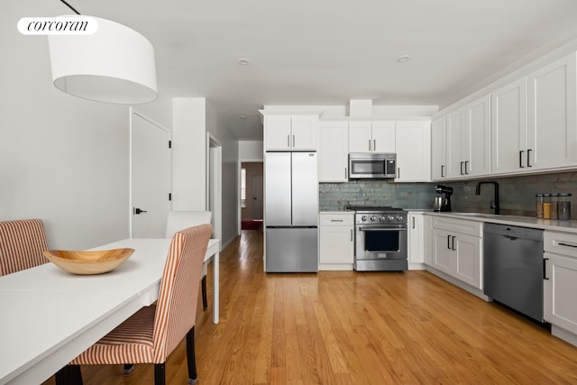 407 Lincoln Rd, New York City, NY 11225 - kitchen with appliances with stainless steel finishes, tasteful backsplash, light countertops, white cabinets, and light wood-type flooring
